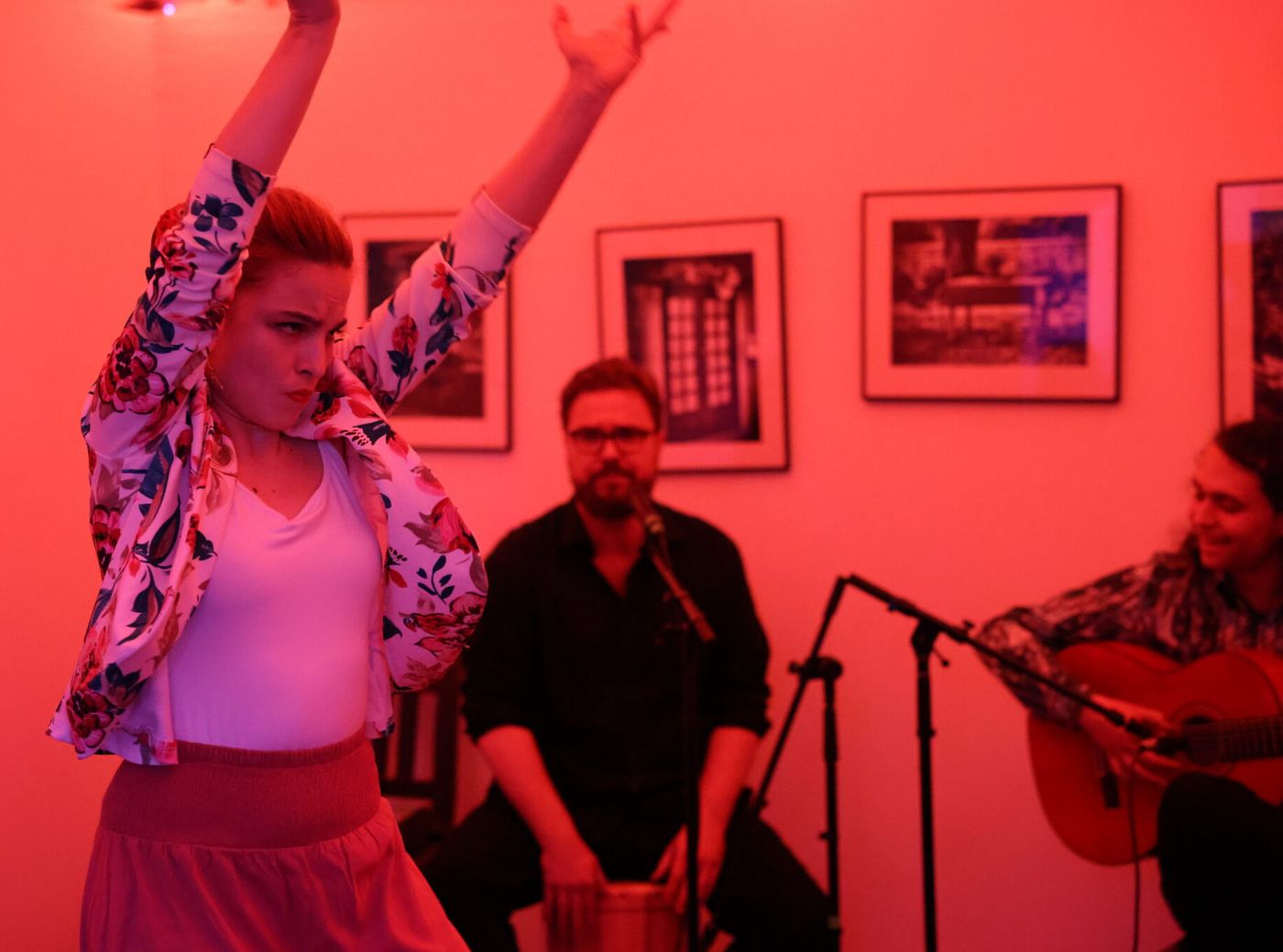 A dancer under red light with singer and guitarist