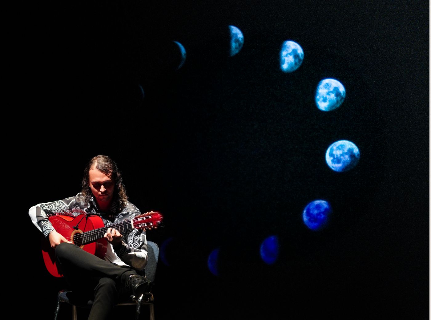 El Cherry playing guitar beneath the phases of the moon
