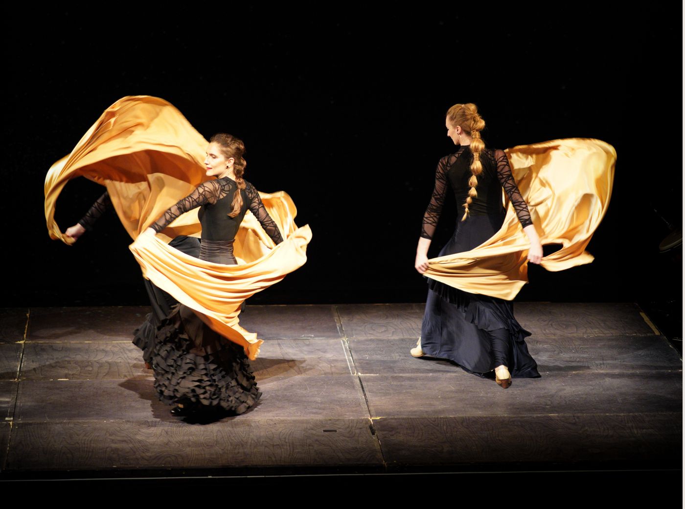 Two dancers swirling golden silk on stage